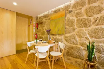 a dining room with a stone wall and a table and chairs at Miragaia Rio in Porto