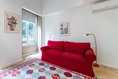 a red couch in a living room with a rug at GuestReady - Belas Artes Duplex in Porto
