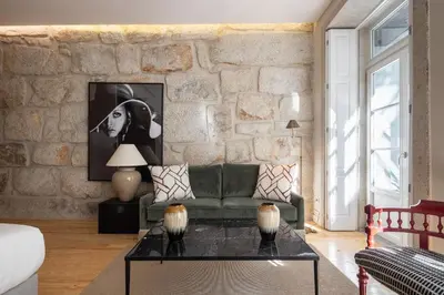 a living room with a green couch and a stone wall at Líbere Porto Laranjais in Porto