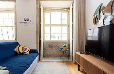 a living room with a blue couch and a flat screen tv at Oporto Blue Almada - Deluxe Citycenter Flat in Porto