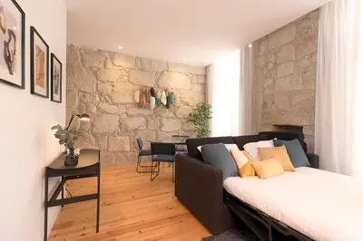 a bedroom with a bed and a stone wall at HM – Oporto Downtown Swimming Pool Apartment in Porto