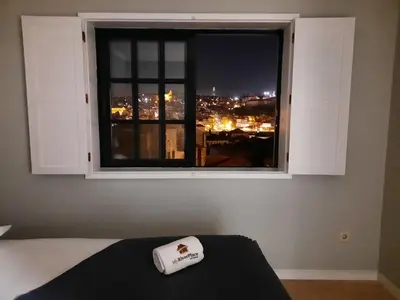 a bedroom with a window with a view of a city at MyRiverPlace N 5 River View Porto apartments in Vila Nova de Gaia
