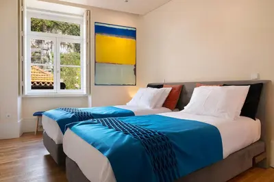 two beds in a room with two windows at Ribeira Trendy Flat in Medieval Mercadores Street in Porto