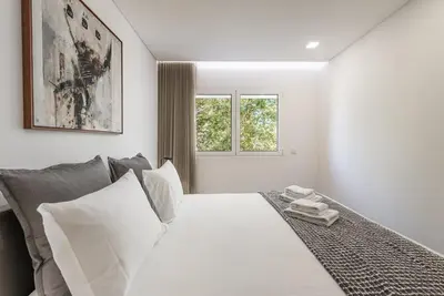 a bedroom with a white bed with two windows at GuestReady - Tigerlily in Porto