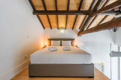 a bedroom with a large white bed with wooden ceilings at GuestReady - RiverWood Mezz in Porto