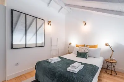 a white bedroom with a large bed with a window at GuestReady - Ladder Mezz in Porto
