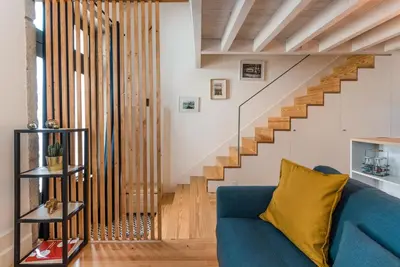 a living room with a blue couch and stairs at GuestReady - Ladder Mezz in Porto