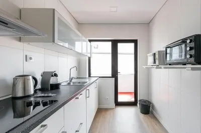 a white kitchen with a sink and a microwave at GuestReady - Music Area in Porto