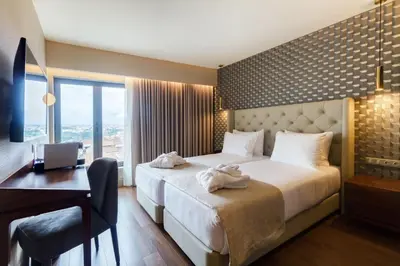 a hotel room with a bed and a desk and a window at Oca Oriental Porto Hotel in Porto