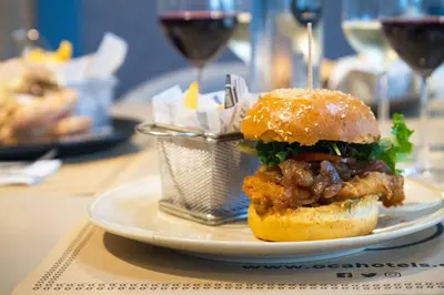 a sandwich on a plate on a table with glasses of wine at Oca Oriental Porto Hotel in Porto