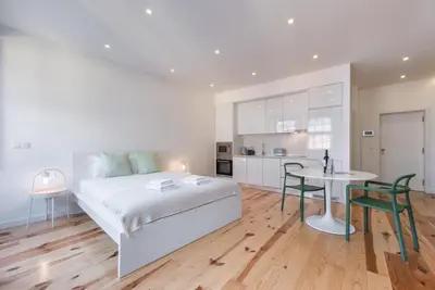 a bedroom with a bed and a table and a kitchen at GuestReady - Mezuzah Yellow in Porto
