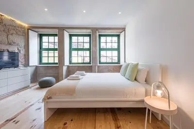 a white bedroom with a large bed and windows at GuestReady - Mezuzah Yellow in Porto