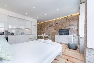 a bedroom with a white bed and a stone wall at GuestReady - Mezuzah Yellow in Porto