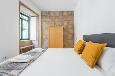 a bedroom with a large bed with yellow pillows at GuestReady - Mezuzah Green in Porto