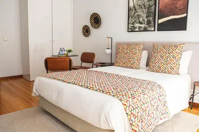 a bedroom with a large white bed with colorful pillows at Impar Studios Deluxe in Porto