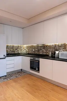 a kitchen with white cabinets and a wooden floor at Ninho @ Francos in Porto