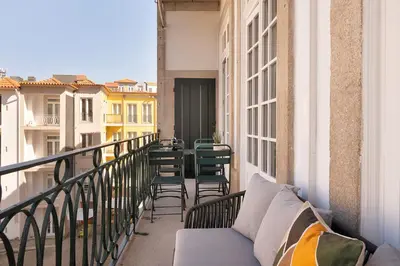 a balcony with chairs and a couch on a balcony at Historic apartment at Cardosas with balcony in Porto