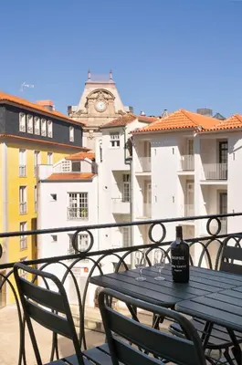 a table and chairs on a balcony with a clock tower at Historic apartment at Cardosas with balcony in Porto
