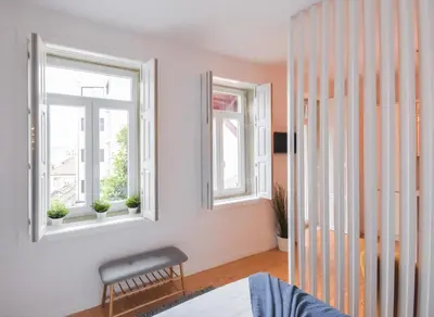 a bedroom with white walls and two windows at Sweet Home Firmeza in Porto