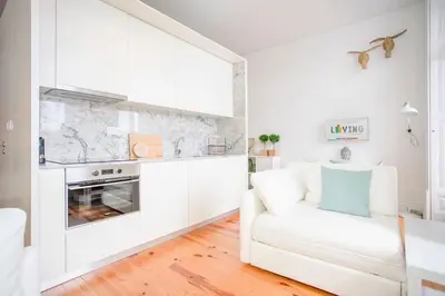 a white living room with a white couch and a kitchen at Liiiving in Porto - Downtown Balcony Studio in Porto