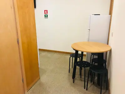 a table and stools in a room with a refrigerator at Congregados Apartment in Porto