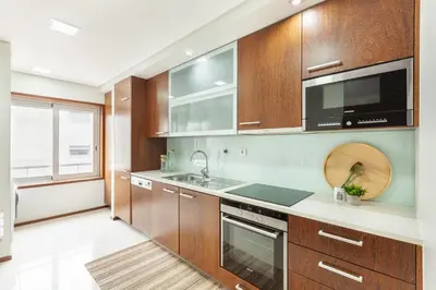 a kitchen with wooden cabinets and a sink and a microwave at D&S - Family Apartments II in Porto
