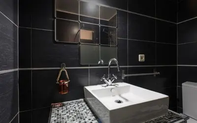 a bathroom with a white sink and black tiles at Silver Duque in Porto