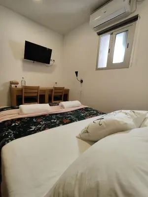 two beds in a room with a tv on the wall at Get Cozy in Porto