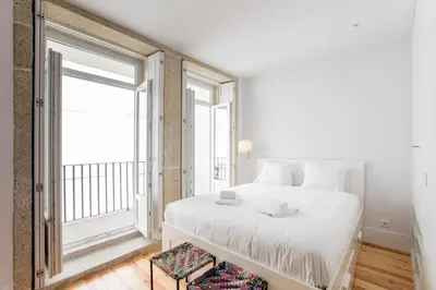 a bedroom with a white bed and a large window at Flux Art Studio w/ AC & Balcony by LovelyStay in Porto