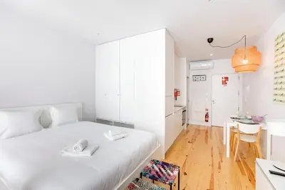 a white bedroom with a white bed and a table at Flux Art Studio w/ AC & Balcony by LovelyStay in Porto