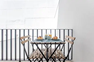 a table with two chairs and food on a balcony at Flux Art Studio w/ AC & Balcony by LovelyStay in Porto
