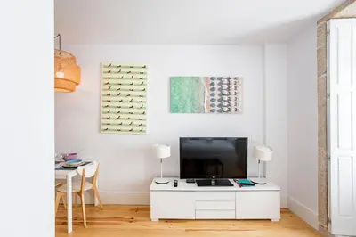 a white living room with a tv and a table at Flux Art Studio w/ AC & Balcony by LovelyStay in Porto