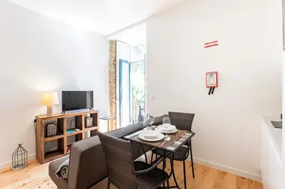 a living room with a table and chairs and a television at Central Studio with Pool & Patio by LovelyStay in Porto