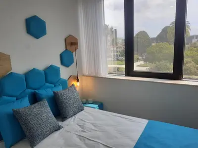a bed with a blue headboard in a room with windows at 3 Bedrooms Central Apartment with garage by Great&Cosy in Porto