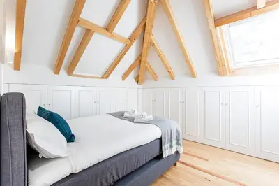 a bedroom with a bed with white walls and wooden ceilings at Bright 3BR Flat w/ AC in City Center by LovelyStay in Porto