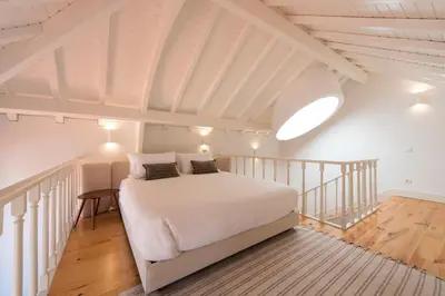 a bedroom with a white bed in a attic at Tripas Coração Taipas Historical Center in Porto