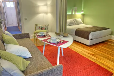a living room with a bed and a table and a couch at Three Houses & Bedrooms in Porto