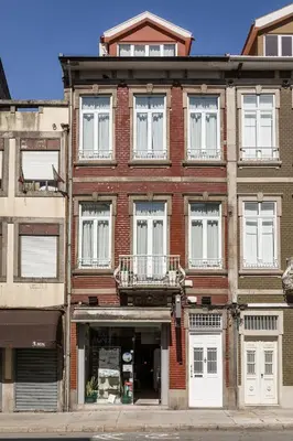 a red brick building with white windows on a street at Carpe Diem Apartments in Porto