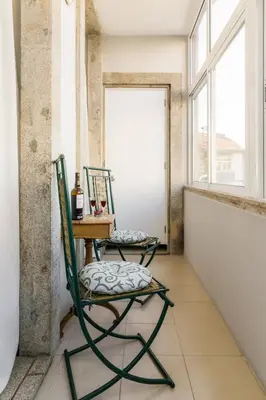 two chairs and a table in a room with windows at Carpe Diem Apartments in Porto