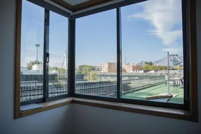 a room with four windows with a tennis court outside at Estúdio Corujeira in Porto