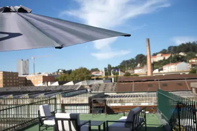 a table and chairs with an umbrella on a roof at Estúdio Corujeira in Porto