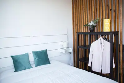 a bedroom with a white bed and a black shelf at Estúdio Corujeira in Porto