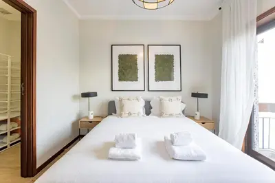 a white bedroom with a large white bed with two mirrors at 2BR Flat in Bonfim w/ AC & Balcony by LovelyStay in Porto
