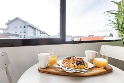 a table with a plate of food and orange juice at 2BR Flat in Bonfim w/ AC & Balcony by LovelyStay in Porto