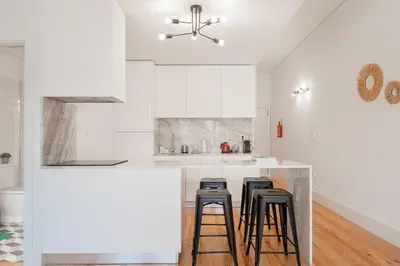a kitchen with white cabinets and a counter with stools at Oporto Shine in Porto