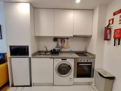 a kitchen with white cabinets and a washing machine at Cais de Gaia Historic Loft in Vila Nova de Gaia