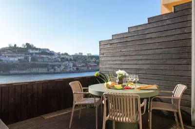 a table on a balcony with a view of the water at Luxurious Townhome with River View by LovelyStay in Porto