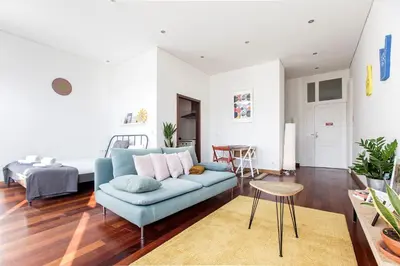 a living room with a blue couch and a bed at Bonjardim Studio w/ Balcony by LovelyStay in Porto