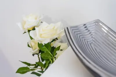 a bouquet of white roses sitting next to a plate at Papa 1T · Papa Studio Central Garden View in Porto
