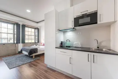 a kitchen with white cabinets and a bed in a room at Papa 1T · Papa Studio Central Garden View in Porto
